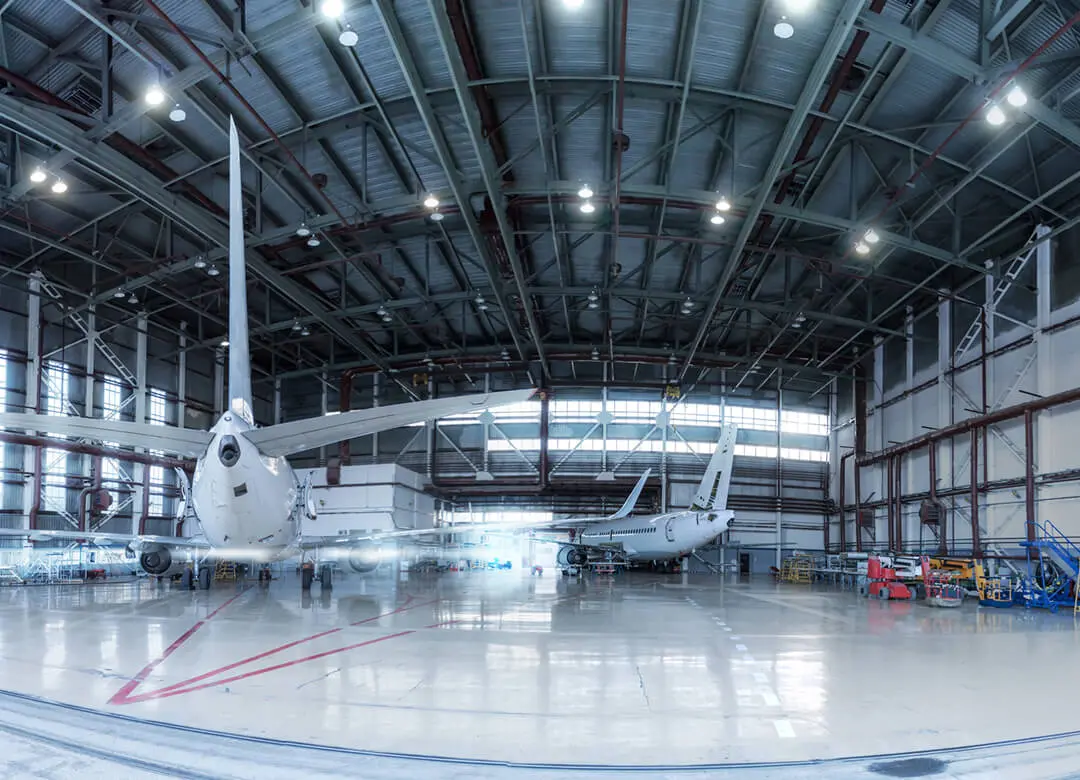 Airplanes parked inside large aircraft hangar.