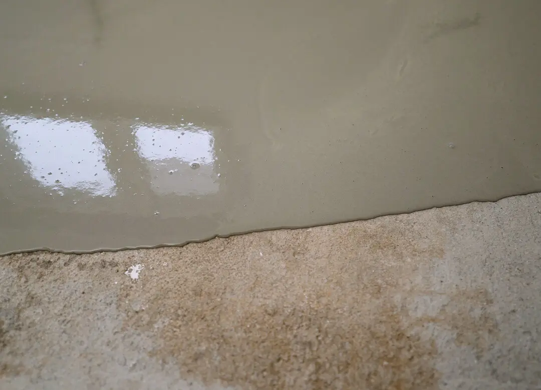 Wet concrete poured on rough floor surface.