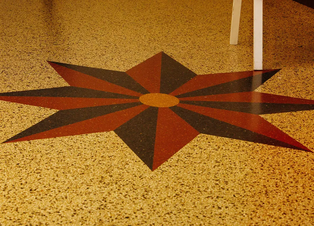 Star pattern on speckled floor, partial chair.